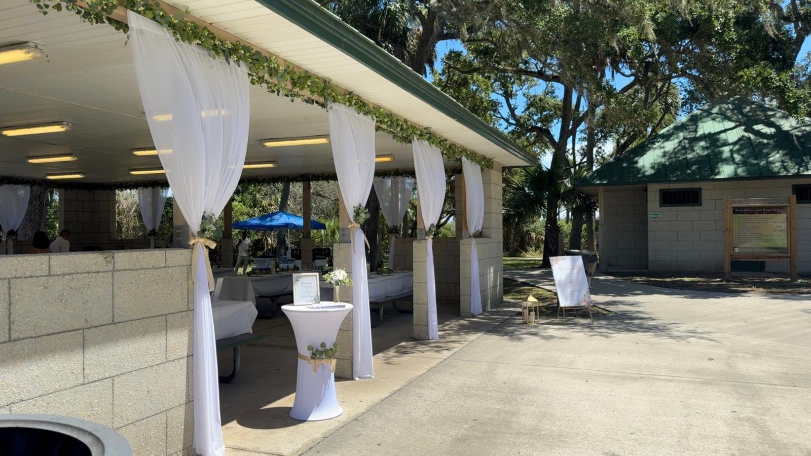 Pavilion decorated with white draping and elegant welcome tables