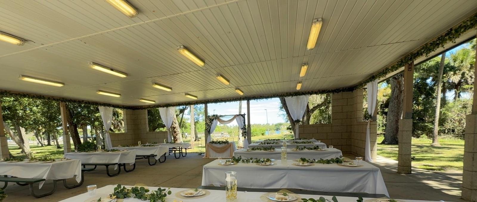 Reception tables facing the floral sweetheart backdrop inside the pavilion