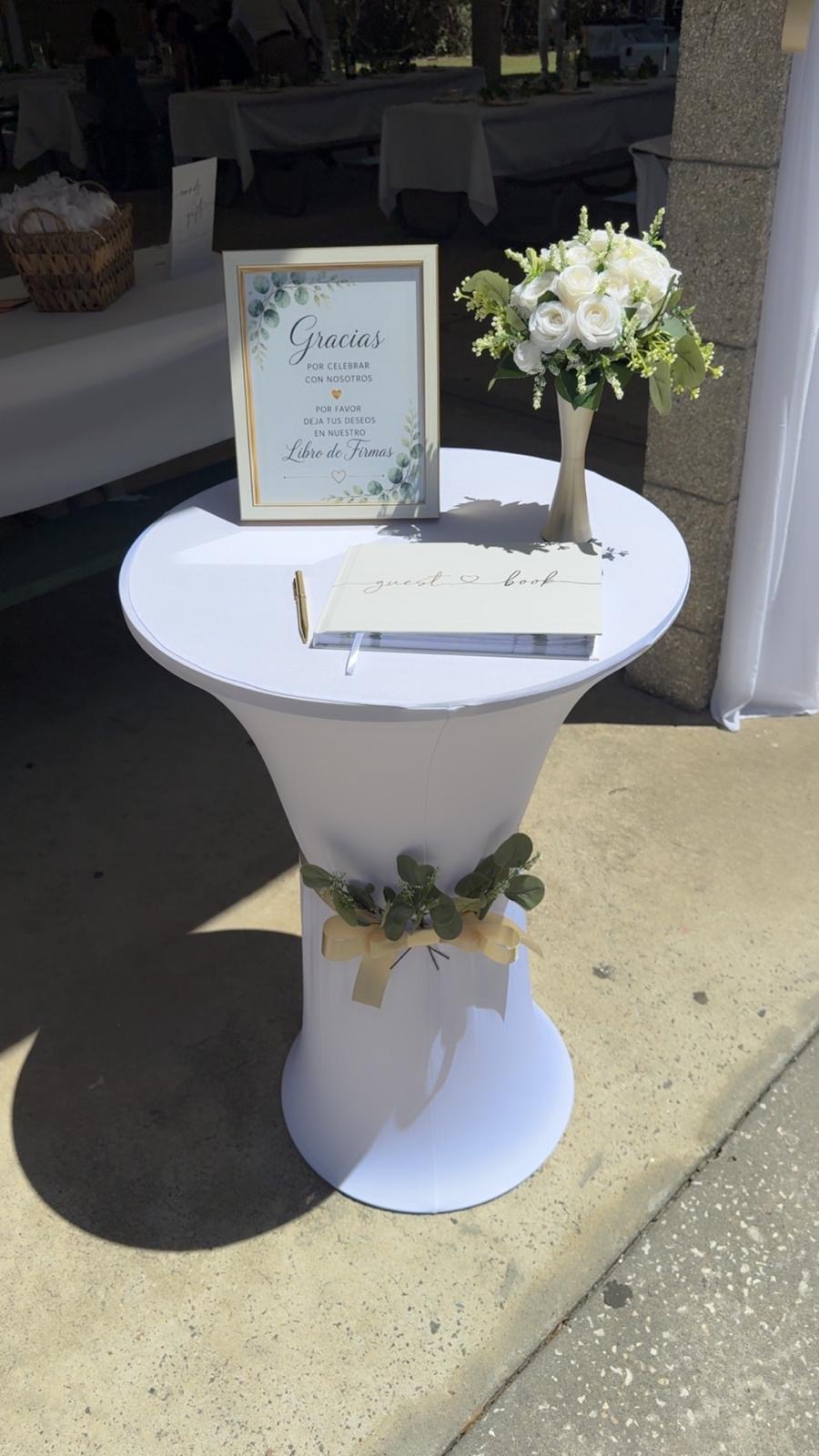 White welcome cocktail table decorated with greenery and flowers