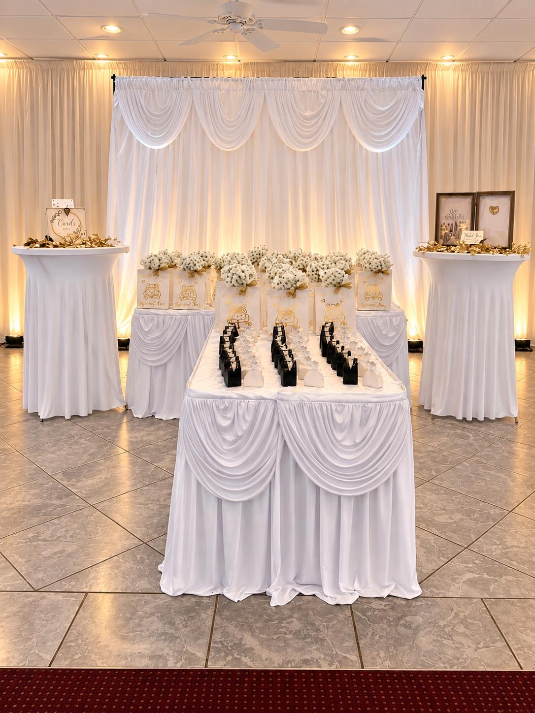 White and gold wedding favor display with illuminated draping