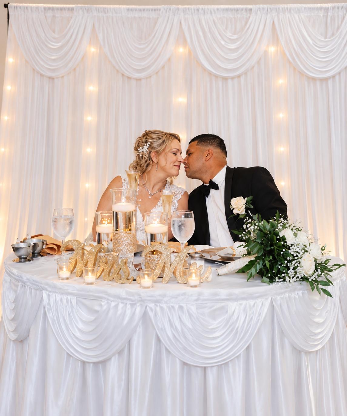 Newlyweds seated at an elegant sweetheart table with candles and flowers
