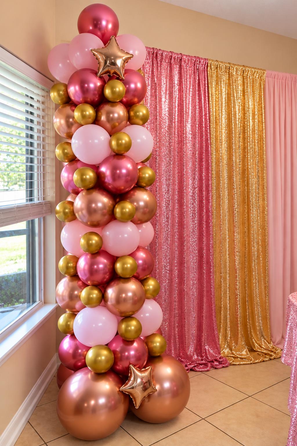 Rose-gold, blush, and burgundy balloon column beside a shimmering curtain